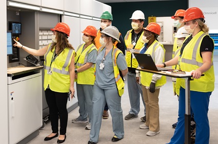 Wearing hard hats and bright safety vests, a group of employees tours a unit in the Pavlion.